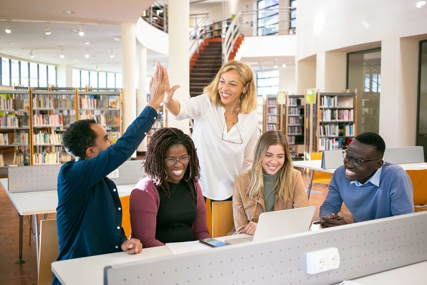 Students and a teacher celebrating together in a library